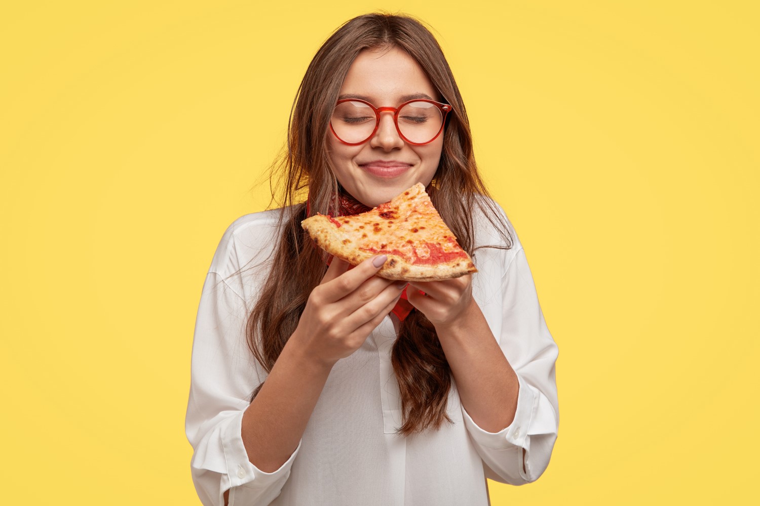 Mulher jovem come um pedaço de pizza.