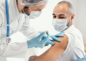 Fotografia colorida de homem sendo vacinado.