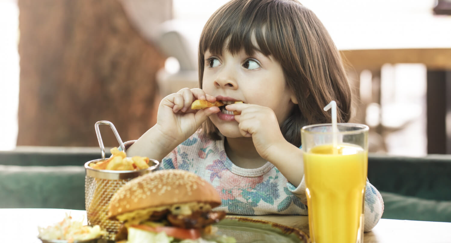 Criança comendo alimentos não saudáveis