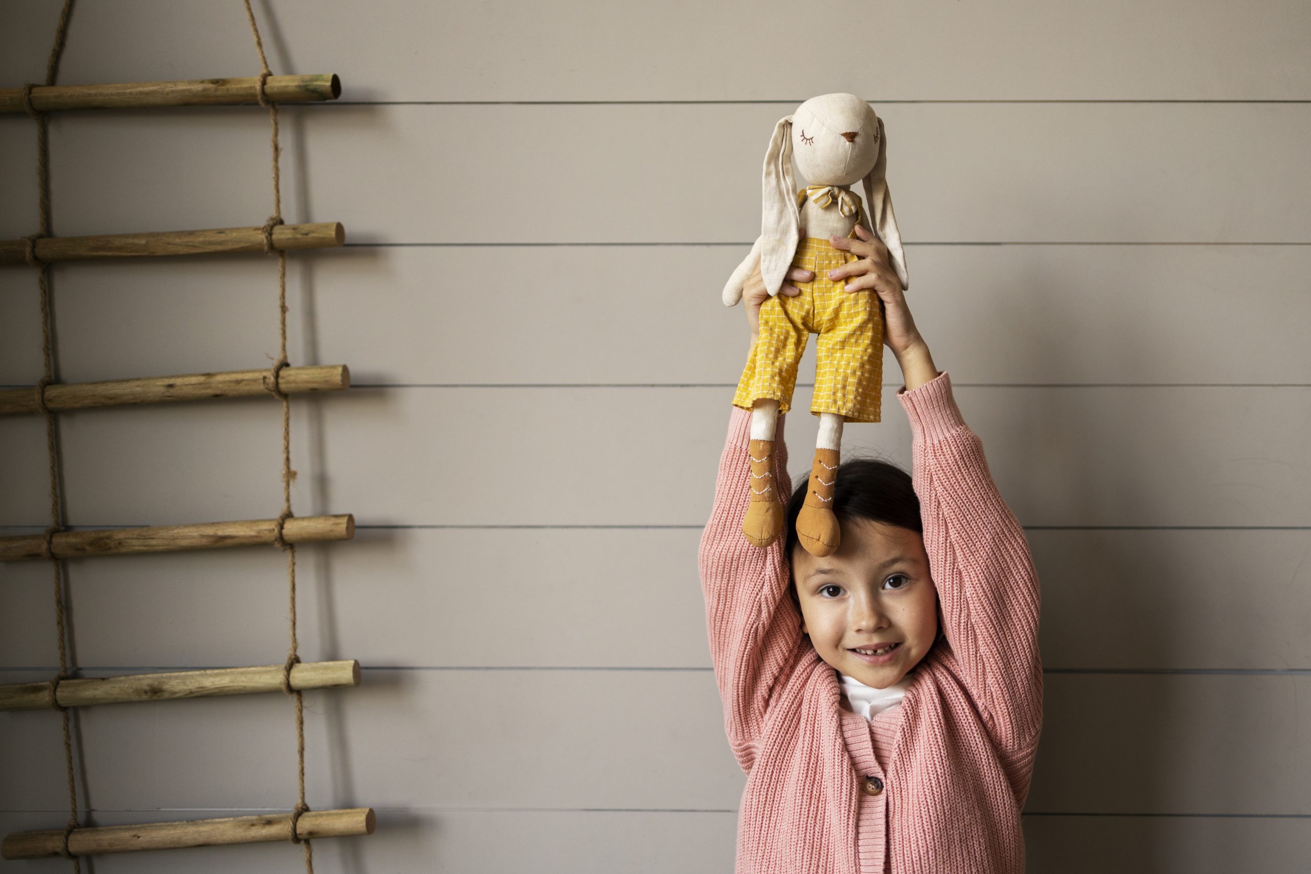 Criança segurando boneco no alto.